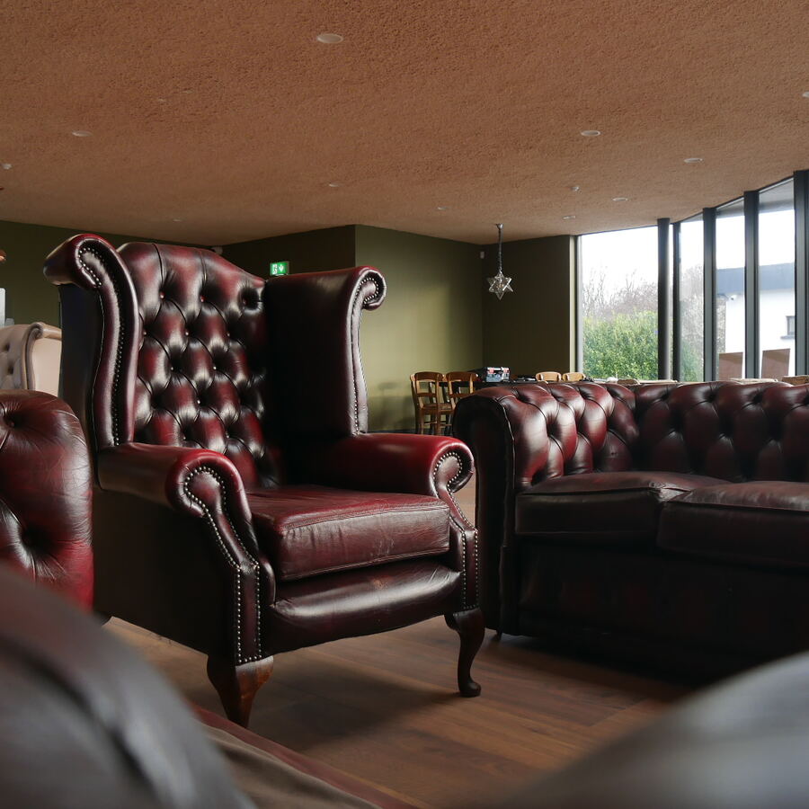 A red leather wingback armchair beside a green wall.